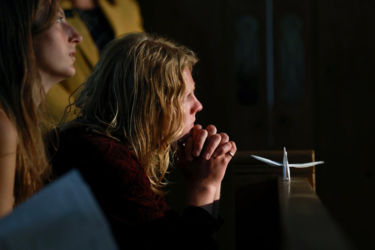 Charlie Stacey '24 sits with an origami crane (folded from program paper) and listens after performing at Baccalaureate on May 17 at Shove Chapel. Photo by Jamie Cotten / Colorado College