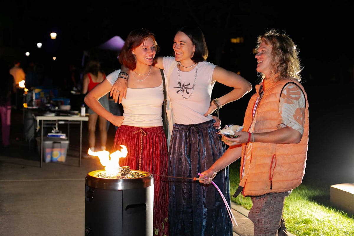 Michaela Kabat ’26, Ami Piburn ’27, and Kieran Blood, a CC alum, mingle and roast marshmallows at the first-ever Campus Sleep-Out on Friday, Sept. 13. Photo by Parker Seibold/Colorado College