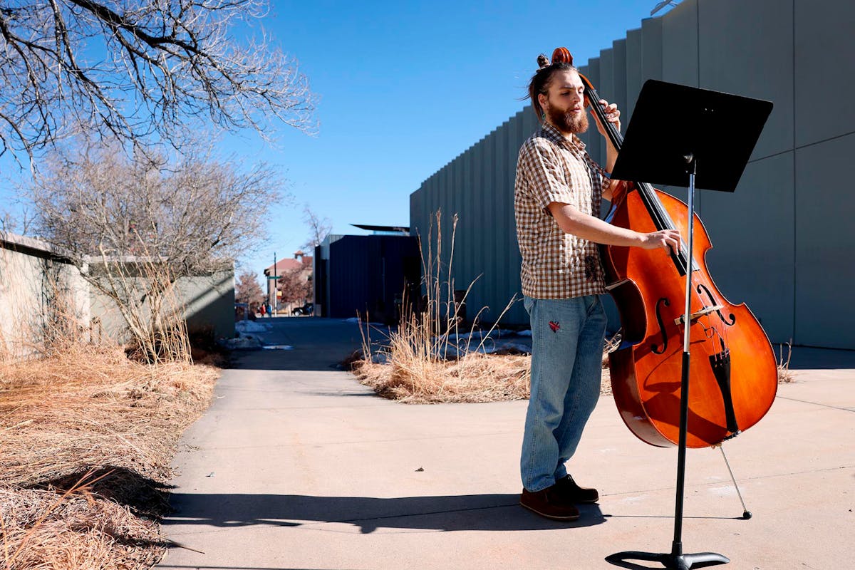 Luca Zoeller ’27 plays bass on Feb. 5 outside Packard Hall. Zoeller said he plays outside every afternoon weather allows. Photo by Jamie Cotten / Colorado College